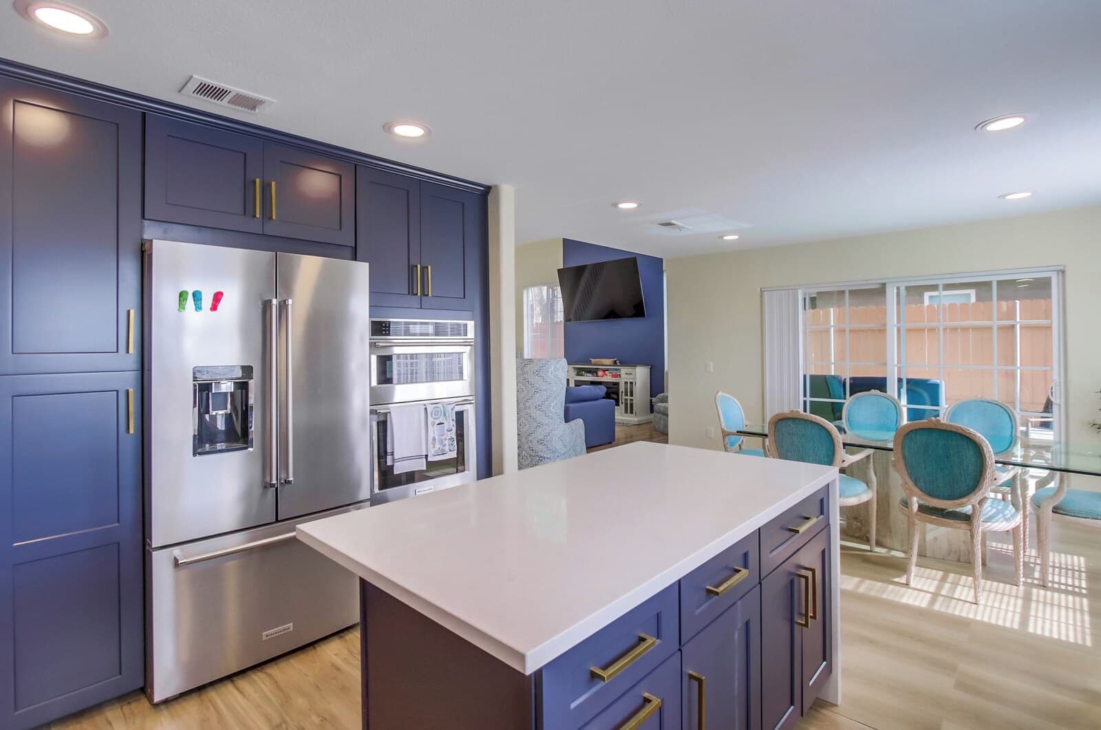 A modern kitchen with dark blue cabinets, stainless steel appliances, and a central island.