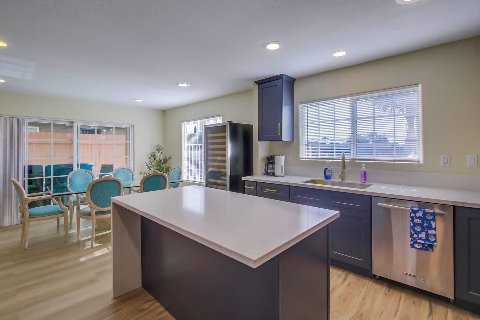 A modern kitchen with a central island, dark cabinetry, a built-in oven, and a large window.