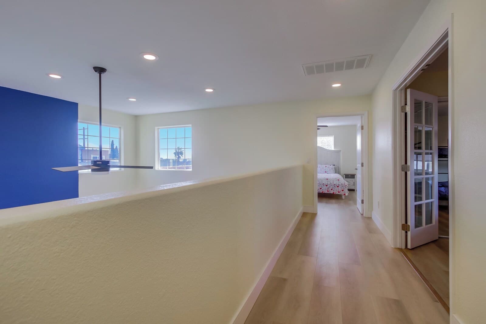 A spacious hallway with a high ceiling, recessed lighting, and a view of the outside through large windows.