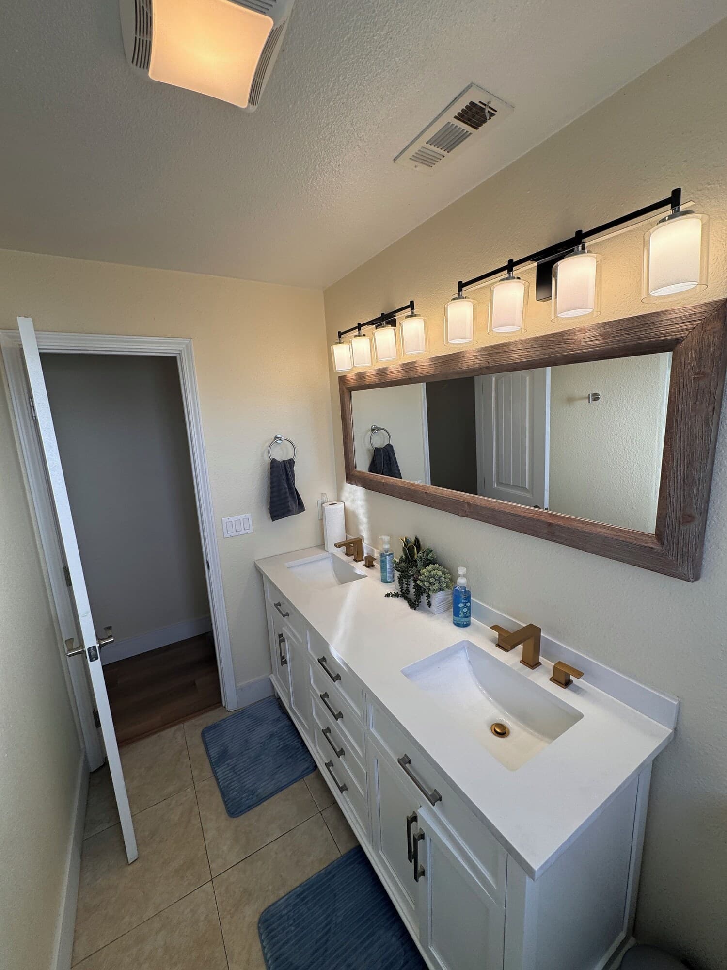 A modern bathroom with a white vanity, a large mirror, and a ceiling light fixture.