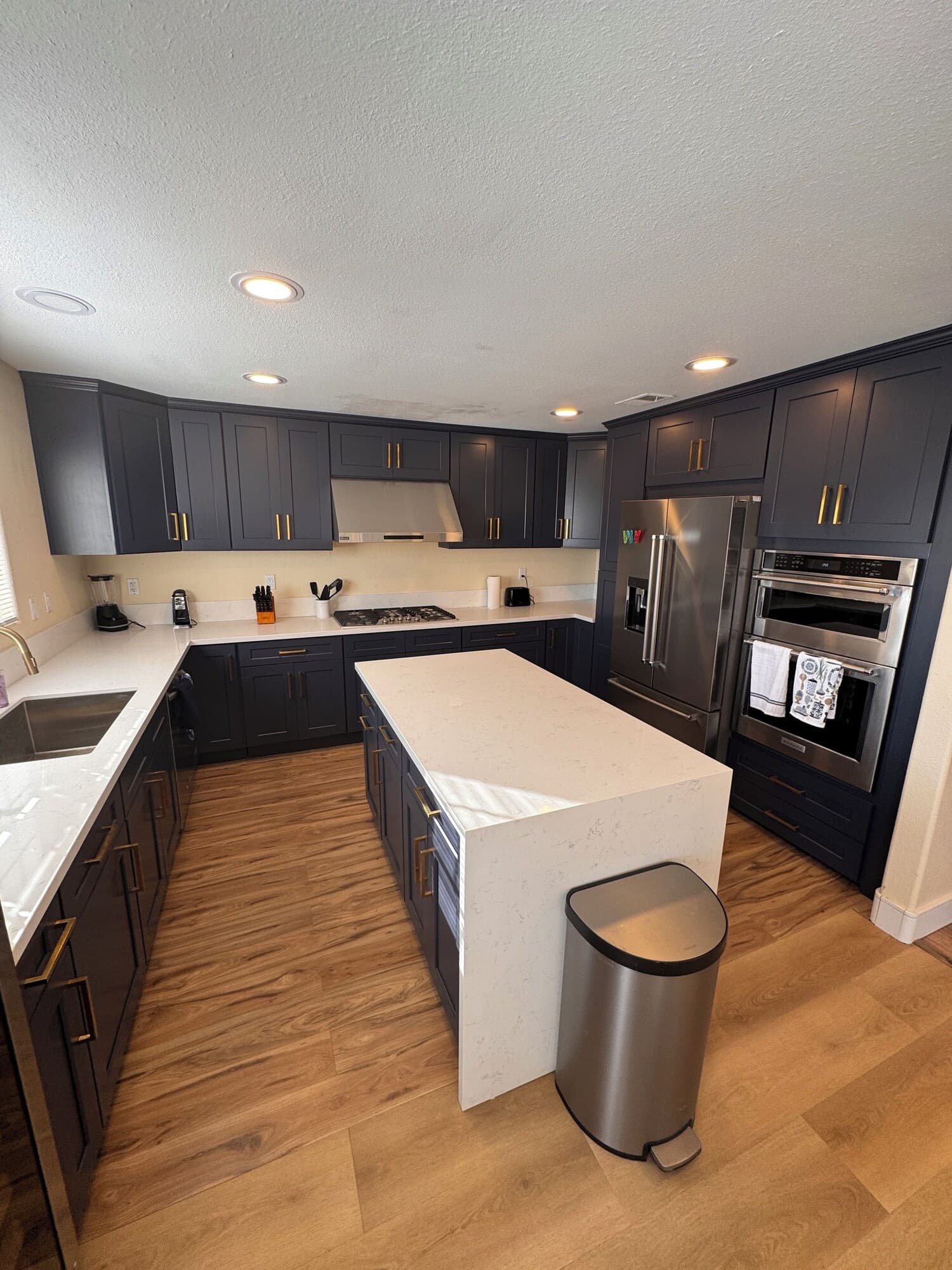 A modern kitchen with dark cabinetry, stainless steel appliances, and a central island.