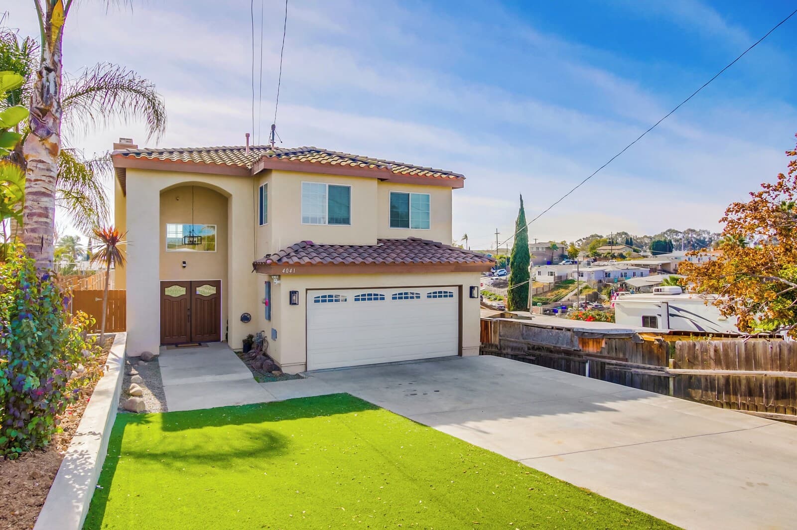 A two-story house with a tiled roof, a garage, and a well-maintained lawn.