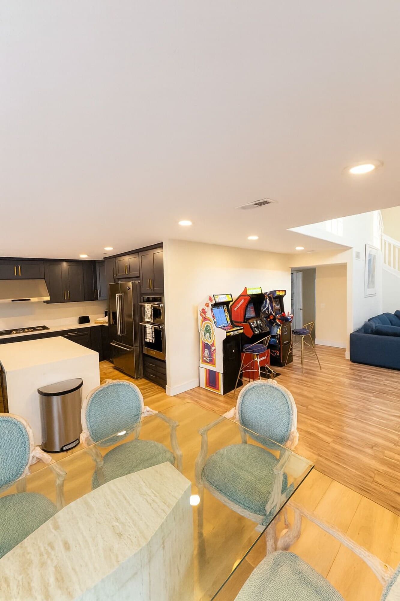 A modern living space with a kitchen, dining area, and arcade games.