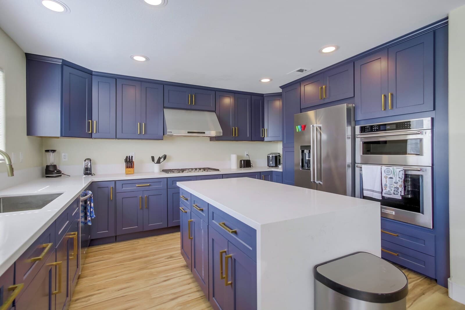 A modern kitchen with blue cabinets, stainless steel appliances, and a central island.