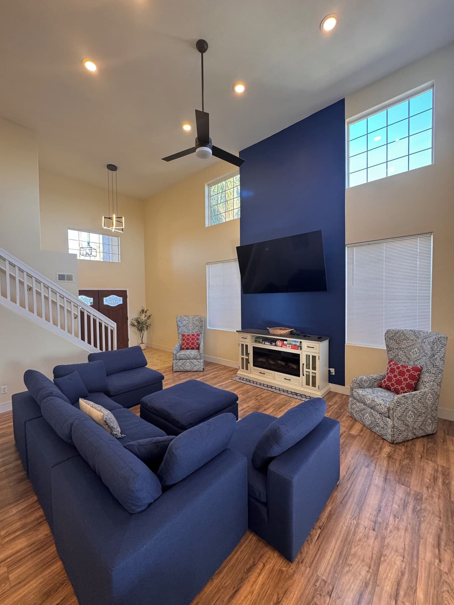 A spacious living room with a sectional sofa, a fireplace, a television, and a staircase leading to another level.