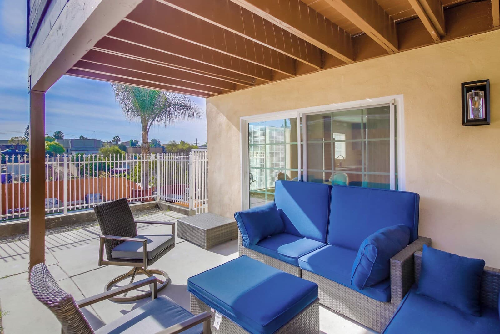 A covered outdoor seating area with wicker furniture and a blue sofa.