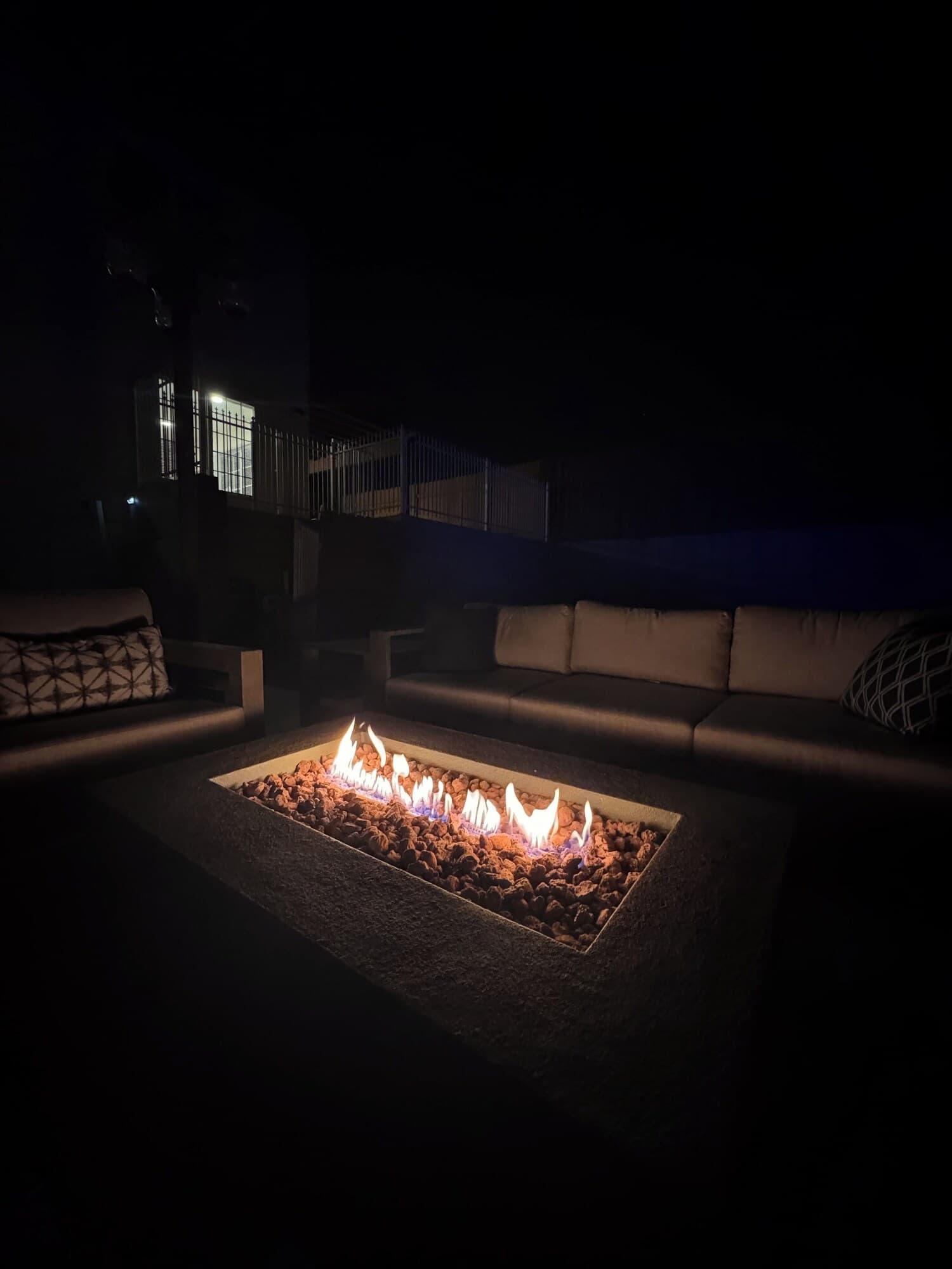 A dark outdoor seating area with a fire pit in the center.