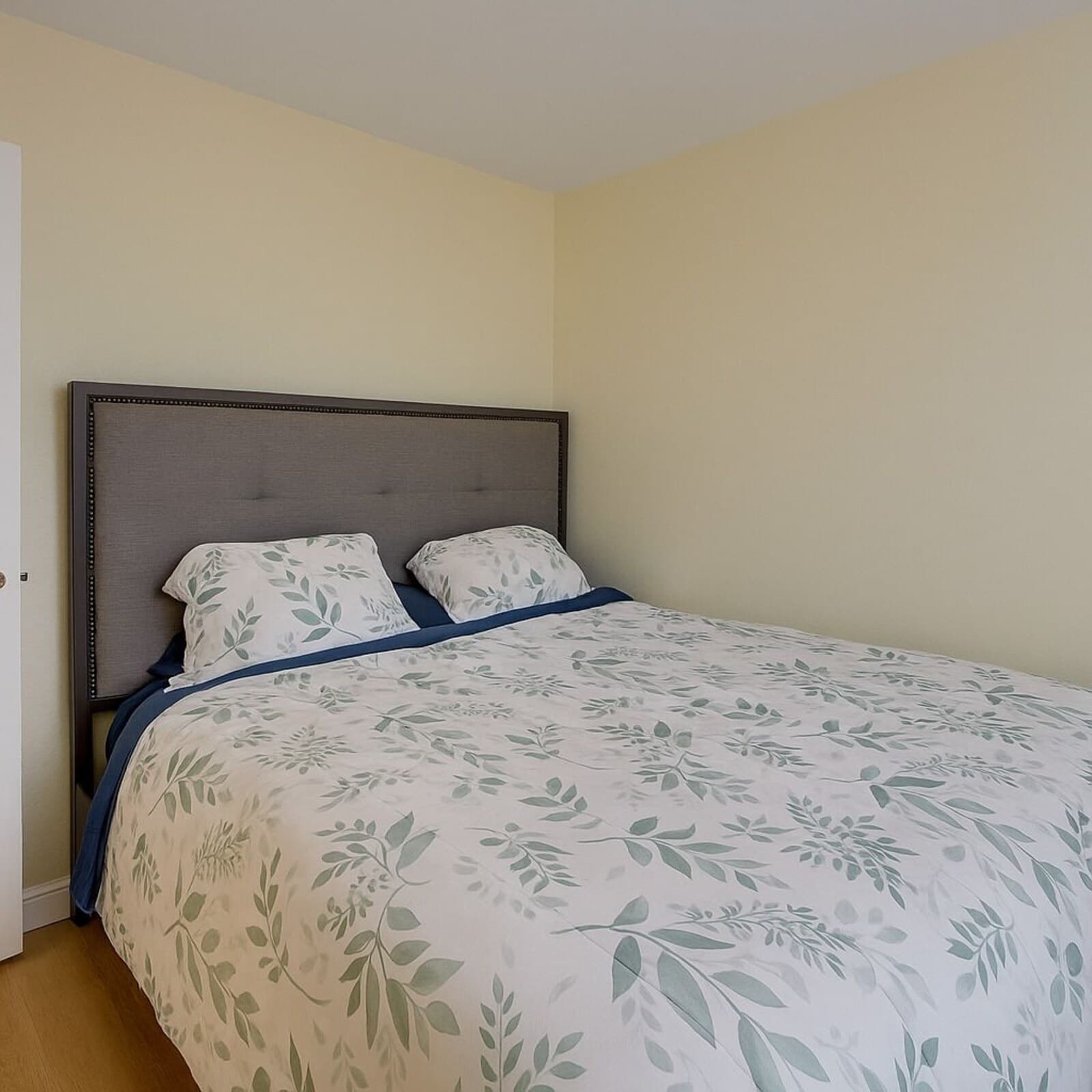 A bedroom with a bed, a headboard, and a door.